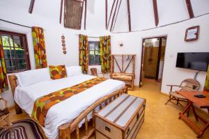 a bedroom with a large bed and a tv at Etana Cottage in Kakamega