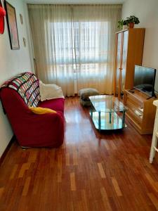 un soggiorno con divano rosso e tavolo in vetro di Apartamentos Virita Coqueto Apartamento vacacional, próximo a la playa a La Coruña