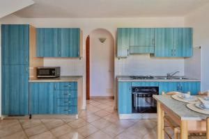 een keuken met blauwe kasten en een tafel bij Graziosi appartamenti a Budoni con aria condizionata a soli 300 mt dal mare in Budoni