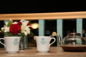 2 tazas de café y un hervidor de agua sobre una mesa en Turquoise Hotel en Áqaba