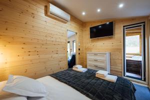 a bedroom with a wooden wall with a bed and a television at Telegdy Homes in Praid