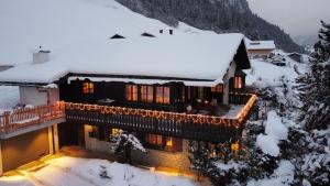 a house covered in snow with lights on it at Chalet Alten in Klosters Dorf