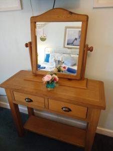 a wooden dresser with a mirror on top of it at Emms Cottage in Par