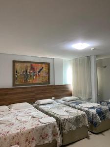 a room with three beds and a painting on the wall at Pousada Orla dos Corais in Maragogi