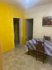 um quarto com uma mesa e uma parede amarela em Maria Dajuda em Guarapari