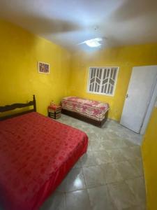 a bedroom with two beds and yellow walls at Maria Dajuda in Guarapari