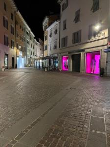 una calle de ciudad vacía por la noche con luces rosas en Appartamento nel Borgo en Rovereto