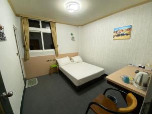 台北市にあるRich Zone Hotelのベッドとデスクが備わる小さな客室です。