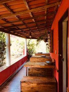 a porch with wooden benches and an orange wall at Pousada Ponte da Ceroula in Palmeiras