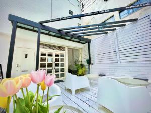a patio with pink flowers and white furniture at En- Hostel & Café bar in Amami