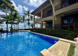 a swimming pool in front of a house at The Backyard Beachfront Hotel in Playa Hermosa