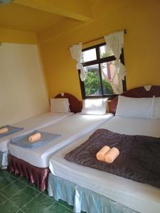 two twin beds in a room with a window at Charung Beach in Haad Rin