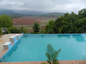 a blue swimming pool with a view of a mountain at THE NIHAL RESORT in Mahabaleshwar