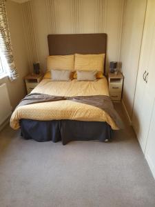 een slaapkamer met een groot bed met 2 nachtkastjes bij Kingfisher Lodge in Felton