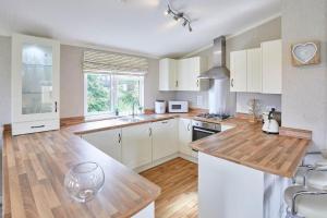 a kitchen with white cabinets and a wooden counter top at Kingfisher Lodge in Felton