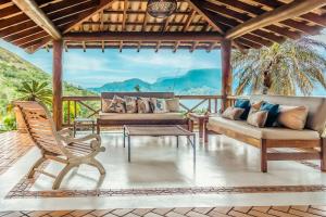 sala de estar con sofá y sillas en el porche en Casa de luxo com vista para o mar em Ilhabela, en Ilhabela