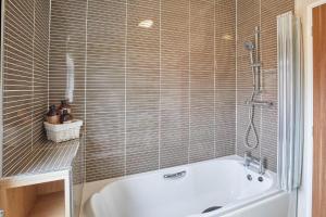 een badkamer met een wit bad en een douche bij Kingfisher Lodge in Felton