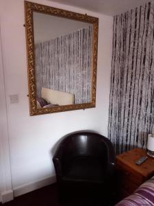 um espelho numa parede ao lado de uma cadeira preta em Aberdeen Arms Hotel Tarland em Tarland