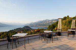 a patio with tables and chairs and a view of the water at Hotel Il Perlo in Bellagio