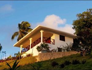 uma casa branca numa colina com uma palmeira em Bungalow de Ballenas em Punta Balandra