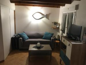 a living room with a couch and a tv at À 150m de la plage in La Bétaudière