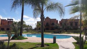 a swimming pool with palm trees in front of a building at Appart atlas resort in Marrakesh