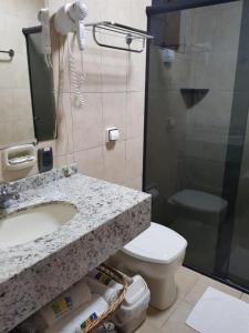 a bathroom with a sink and a toilet and a shower at Pousada Morada das Ilhas in Boicucanga