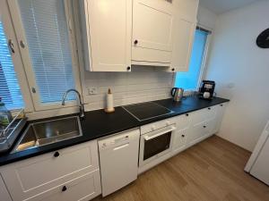 a kitchen with white cabinets and a black counter top at Cosy apartment in the heart of Lahti, free parking in Lahti