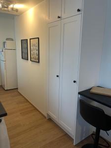 Cosy apartment in the heart of Lahti, free parking في لاهتي: غرفة بها دواليب بيضاء ومكتب وثلاجة