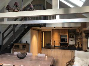 a kitchen and dining room with a table and a staircase at Chalet Bord De L'eau in Bièvre