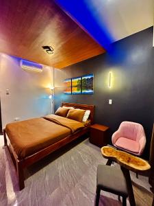 1 dormitorio con 1 cama y 1 silla rosa en Sky Traveller Suites, en Panglao