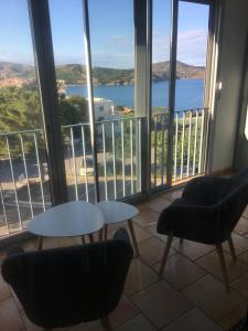 Zimmer mit 2 Stühlen, einem Tisch und Fenstern in der Unterkunft Location Banyuls sur Mer in Banyuls-sur-Mer