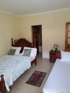 1 dormitorio con 2 camas con sábanas blancas en Casa Alegre en São Filipe