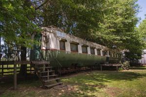 un viejo vagón de tren verde sentado en un campo en Los Vagones de Areco en San Antonio de Areco