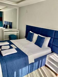 a bedroom with a large bed with blue sheets and pillows at Palmiye Gold in Çiftlikköy