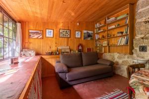 sala de estar con sofá en una habitación con paredes de madera en Chalé da Quinta "Lavoura da Bouça - Fruta Bio" en Celorico de Basto