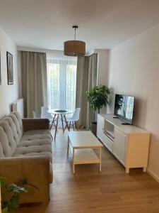 a living room with a couch and a tv and a table at The Botanic Corner Apartment in Wrocław