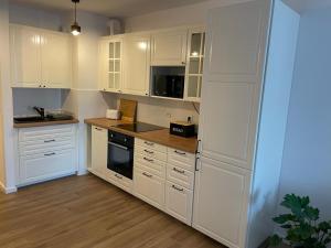uma cozinha com armários brancos e um forno com placa de fogão em The Botanic Corner Apartment em Breslávia