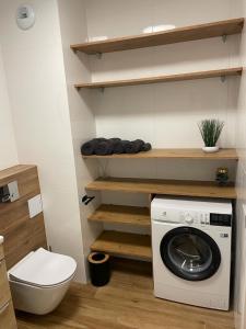 a bathroom with a washing machine and a toilet at The Botanic Corner Apartment in Wrocław
