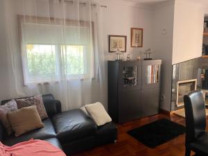a living room with a black couch and a window at ESPAÇO ALVIM in Esmoriz