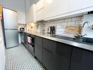 1 Bed Character Filled Glasgow Apartment في غلاسكو: مطبخ بدولاب بيضاء ومغسلة وثلاجة