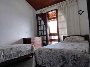 a bedroom with two beds and a door with a window at Uma PAUSA na sua vida, com: sol, praia e sossego! in Cabo Frio