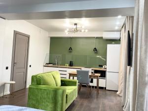 a green kitchen with a green couch and a table at Apartment on KShT in Ustʼ-Kamenogorsk