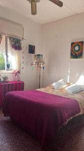 a bedroom with a bed with a purple blanket at Casa con vista a la salida del sol in La Cumbre