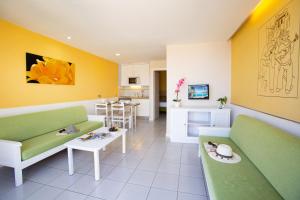 una sala de estar con muebles verdes y blancos y una cocina. en Hotel Riosol, en Puerto Rico de Gran Canaria