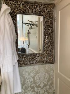 a mirror in a bathroom with a white robe on a wall at GuesthouseOne in Haarlem