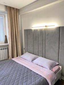 ein Schlafzimmer mit einem großen Bett mit einem grauen Kopfteil in der Unterkunft Apartment on KShT in Öskemen