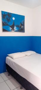 a bed in a blue room with a picture on the wall at Pousada Fortaleza in Fortaleza