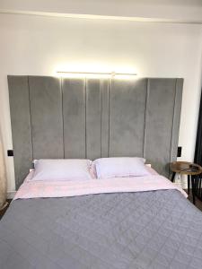 ein großes Bett mit grauem Kopfteil in einem Zimmer in der Unterkunft Apartment on KShT in Öskemen
