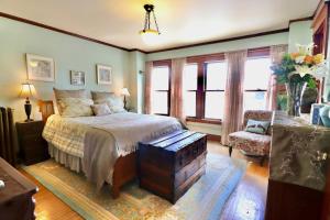 a bedroom with a bed and a chair and windows at The Marshall House in Niagara Falls